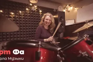 Женщина за пятьдесят с палочками над красной установкой улыбается прямо в камеру – Ударный квартирник, декабрь 2023